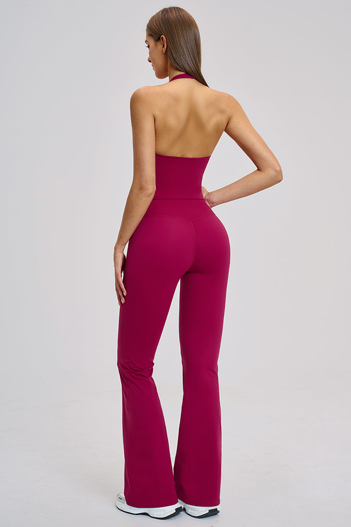 Women's athleisure set in raspberry red: halter V-neck crop top and flared high-rise leggings, back view.